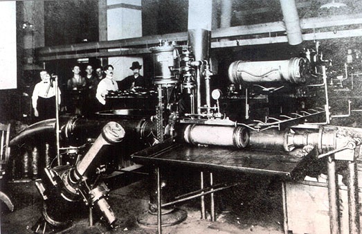 An archival photograph of pneumatic mail machinery and workers in a post office basement