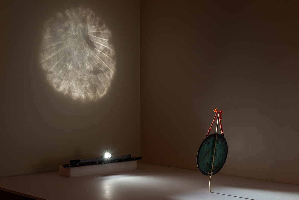 The bronze mirror projecting its concealed Buddha image onto a wall — Rob Deslongchamps / Cincinnati Art Museum. Buddhist bronze mirror x1961.2, original photograph.